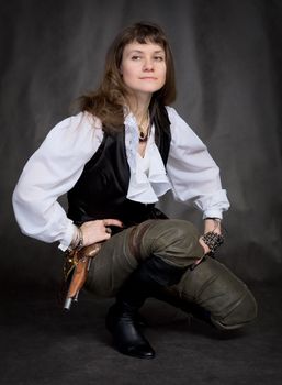 Girl - pirate with pistol sit on black background