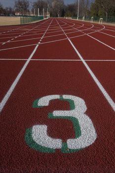 white lane number three at a starting line red running tracks