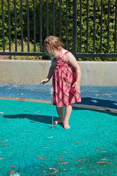 Cute little European toddler girl having fun with water at the playground in park