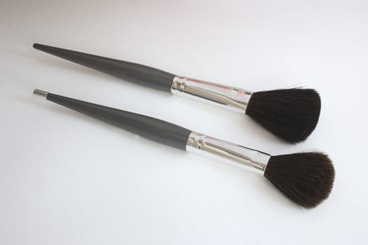 two large makeup brushes with grey and silver handles