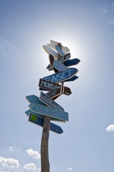 Close-up on lot of signs in only one roadsign to the world surf spots on a beach with a blue sky