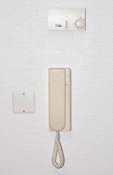 Beige intercom on a white wall with an air conditioning adjuster