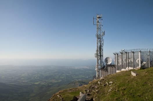 Landscape with antennas and metallic grid on a blue sky