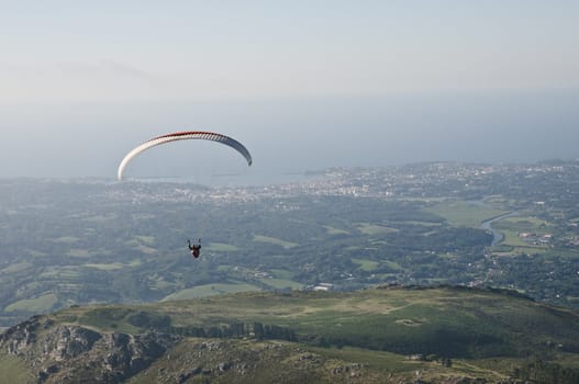 Paraglider man above Atlantic coast and little mountains