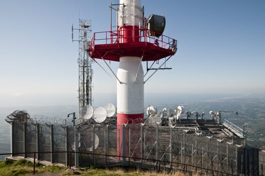 Many dish antennas with a big white and red on a blue sky