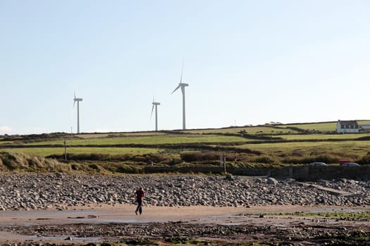 man running on beale beach co kerry ireland on a cold winters morning with turbines in the background