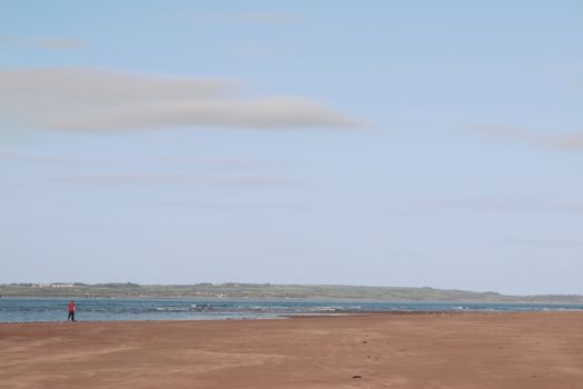 man walking on beale beach co kerry ireland on a cold winters morning with turbines in the background