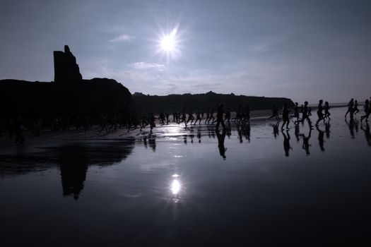 people some dressed in santa hats doing a christmas swim for charity with castle in background