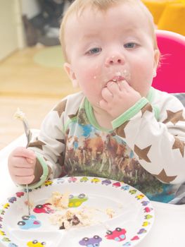 Cute baby toddler on his first birthday eating  cake