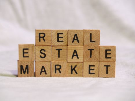 The words REAL ESTATE MARKET spelled out with wooden tiles