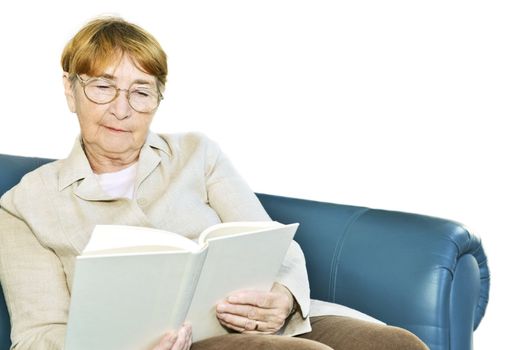 Elderly woman relaxing on couch reading a book