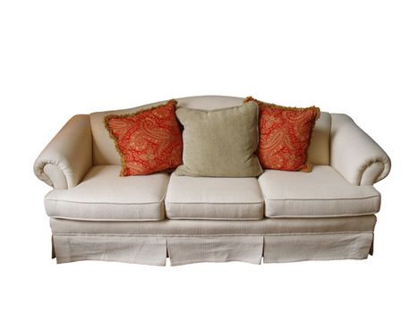 An overstuffed sofa covered in off-white fabric with two paisley pillows and one herringbone pillow isolated on white.
