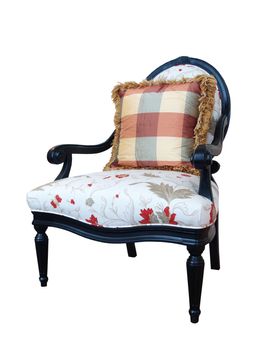 A white upholstered chair with ebony woodwork and a plaid pillow isolated against white.