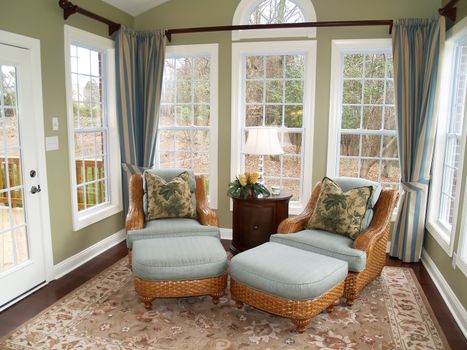 Two comfortable rattan or wicker chairs in a nicely decorated luxury sunroom