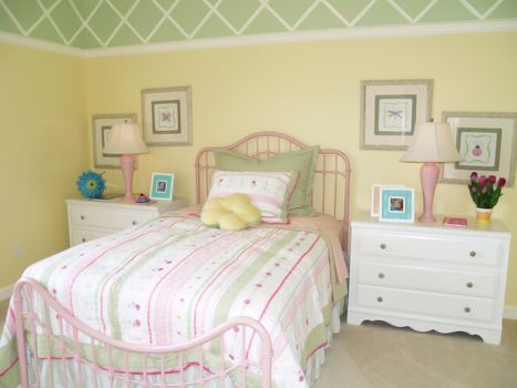 Bright yellow children's bedroom tastefully decorated with a green diamond border at the ceiling. 