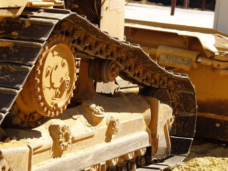 Closeup of the side of a heavy equipment earth moving bulldozer on a dusty construction site.