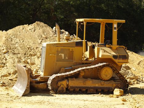 A heavy equipment earth moving bulldozer on a dusty commercial construction site. 