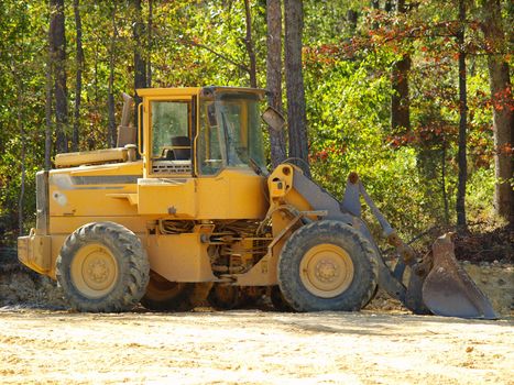 Heavy equipment earth moving front loader on a dusty construction site.