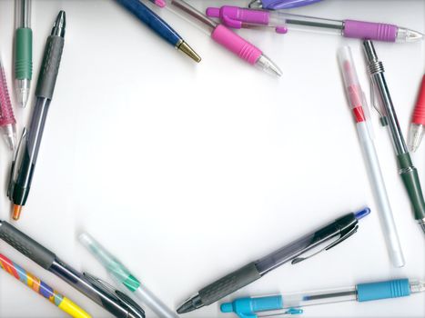 Various pens and pencils arranged around a blank area forming a border.