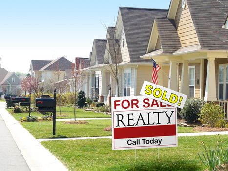 View of a residential street and a real estate for sale sign in the foreground with a prominent SOLD notice.