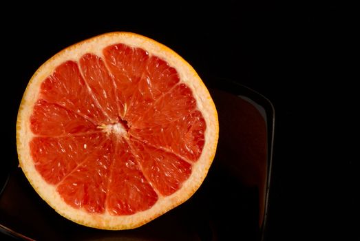 Halved fesh juicy grapefruit on blach background