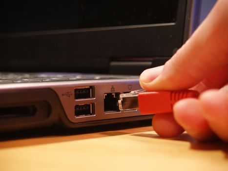 Ethernet connection being plugged into a laptop computer with focus on port