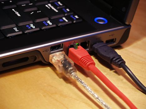 Closeup image of a laptop computer with three cables plugged into the ports