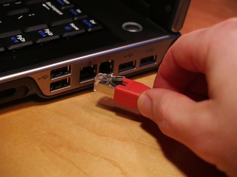 Ethernet cable being plugged into a network port on a laptop computer