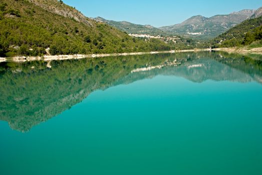 Lake landscape, forests and mountains reflecting in clear water