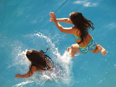 Two sisters jump into the water in tandem