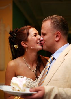 Cheerful groom and the bride kiss, are soiled in a cream