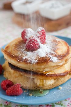 Delicious fresh pancakes being topped with icing sugar