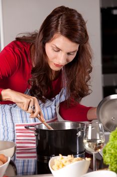 Pretty young woman stirring in the pan of soup