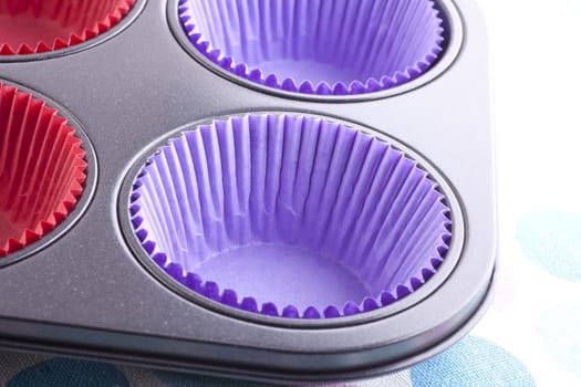 Muffin tin with purple cupcake papers ready to be filled with batter.