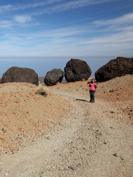 Hiking woman on Teide, Tenerife with a lot of copy space.A view of the hiking path with a backpacker showing many of the big black Teide Eggs or in spanish: Los Huevos del Teide