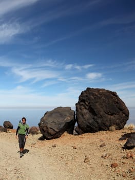 Man Hiking on Teide Tenerife. Man hiking / backpacking on Monta�a Blanca within the national park of Teide on Tenerife. A view of the hiking path showing many of the big black Teide Eggs or in spanish: Los Huevos del Teide. Blue sky for copy space.