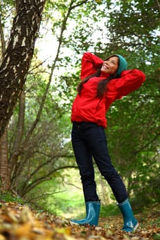 Autumn woman happy and smiling during a walk in the forest during fall