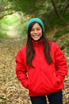 Autumn woman happy and smiling looking at camera during a walk in the forest during fall
