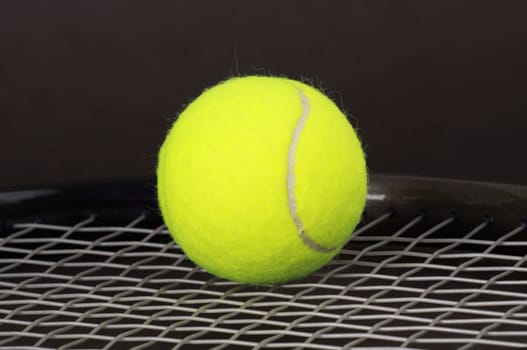 yellow tennis ball over a racket, black background
