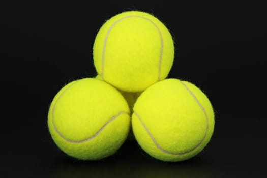 three yellow new tennis ball, black background