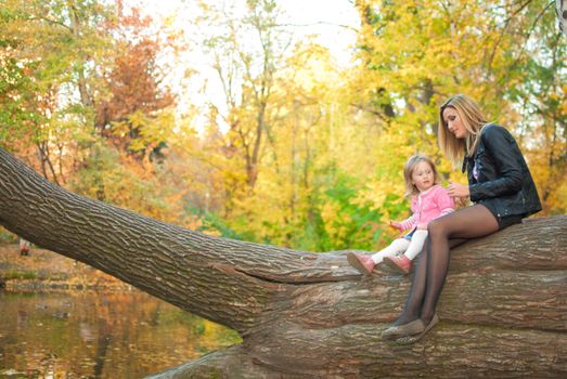 Family pair is sitting on big tree near the pond