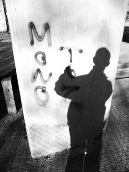 Vandal at work spraying graffiti on a pillar.