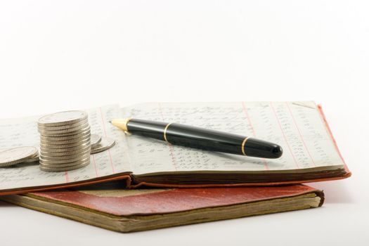 two financial ledgers and a pile of coins on a white background