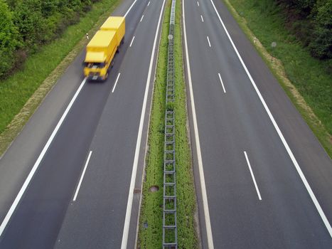 A yellow cargo truck on the German autobahn 
