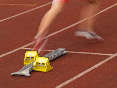 An athlete starts off the starting block at a track and field meeting
