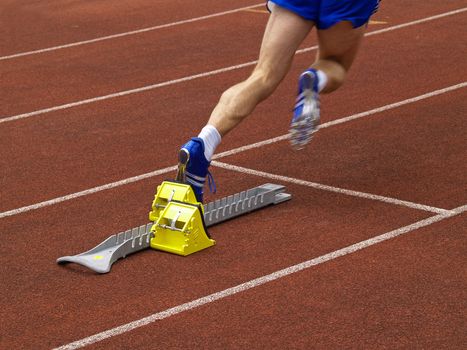 An athlete starts off the starting block at a track and field meeting
