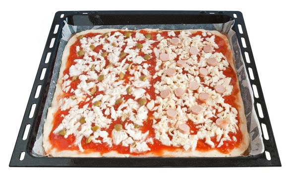 raw pizza with tomato mozzarella and olives on a baking pan