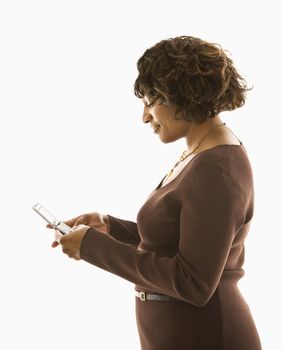 Woman pushing buttons on cellphone standing against white background.