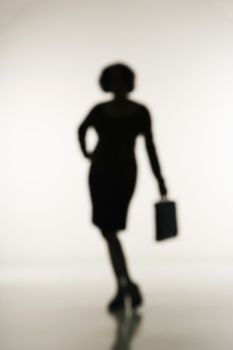 Soft focus silhouette of businesswoman holding briefcase.