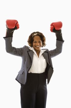 Businesswoman wearing boxing gloves holding arms up in victory stance and smiling.